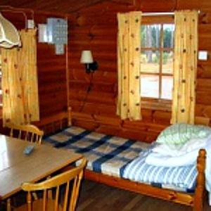 Cabaña de madera con cama y ventana en Mullsjö Camping en Mullsjö