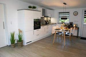 a kitchen with white cabinets and a table with chairs at Ferienhaus Stamer in Eckernförde