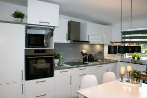 a white kitchen with white cabinets and a table at Ferienhaus Stamer in Eckernförde +17 photos