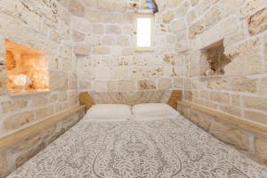 een slaapkamer met een bed in een stenen muur bij Villetta Giardino dei Trulli in Ostuni