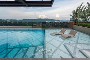 a swimming pool with two chairs on a building at Mossaz at Empire Damansara by Wodages in Kuala Selangor