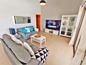 ein Wohnzimmer mit Sofa und Fernseher in der Unterkunft Serena Luxury House in Caleta de Fuste