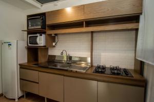 Una pequeña cocina con fregadero y microondas. en Casa Container, 15 min da Praia no Campeche SUL91, en Florianópolis