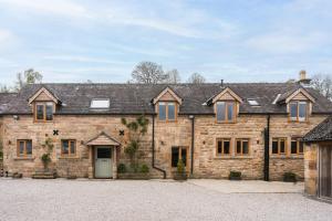 an exterior view of a large stone house at Oker Farm - Luxury farmhouse with hot tub in the Peak District in Matlock +51 photos