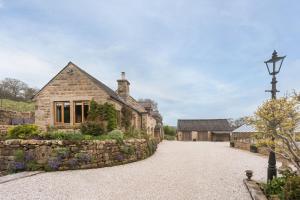 an old stone house with a stone driveway at Oker Farm - Luxury farmhouse with hot tub in the Peak District in Matlock