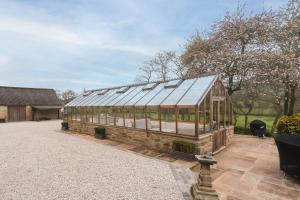 a glass greenhouse in a garden with a building at Oker Farm - Luxury farmhouse with hot tub in the Peak District in Matlock