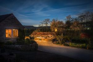 a greenhouse in the yard of a house at night at Oker Farm - Luxury farmhouse with hot tub in the Peak District in Matlock