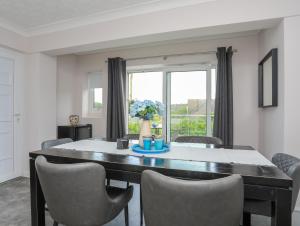 a dining room with a table and chairs and a window at Swn Y Mor in Benllech