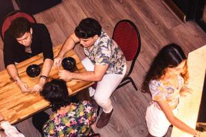 a group of people sitting around a wooden table at The Clock Hostel & Suites in Cartagena de Indias