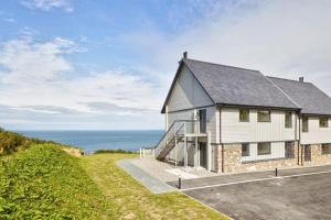 a white house with the ocean in the background at 2 Bed Penthouse Apartment - 14 in Nefyn