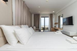 a white bed with white pillows and a television at Lux Hotel M - Boutique Hotel & Restaurant in Dobra Voda