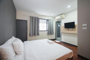 Un dormitorio con una cama blanca y un televisor. en GO INN BTS ST Louis Silom - โกอินน์ บีทีเอส เซนต์หลุยส์ สีลม 4, en Yan Nawa