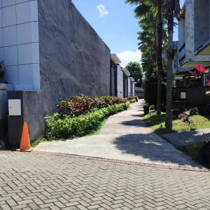 a brick sidewalk next to a building with trees and plants at UU villa at kingspark 8 in Batu