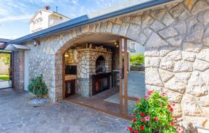 een stenen gebouw met een boog in een tuin bij 1 Bedroom Nice Apartment In Bogovici in Malinska