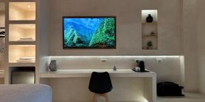 a bedroom with a bed and a television on the wall at Salida Del Sol Santorini in Éxo Goniá +17 photos