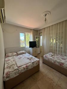 a bedroom with two beds and a television in it at Cicek Aile Pansiyonu in Burhaniye
