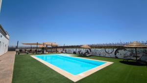 a swimming pool with green grass and umbrellas at LA BENDITA LOCURA in El Puerto de Santa María