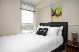a bedroom with a white bed and a window at Hendrix Luxury Apartments by Corporate Stays in Edmonton