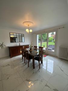 a dining room with a table and chairs on a marble floor at Villa Les Tourelles in Flers