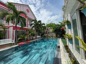 a swimming pool in front of a building at Red House Homestay - Villa in Hoi An