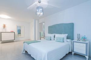 a white bedroom with a large white bed with blue pillows at Casa Mazagón con vistas al mar in Mazagón