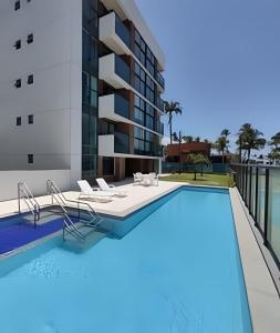 una imagen de una piscina con sillas y un edificio en Rio Park Av, Sea View One - by TRH Home Stay, en Recife