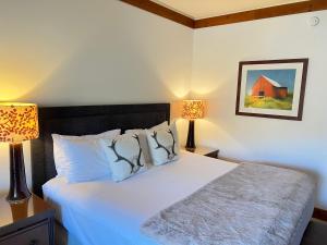 a bedroom with a large white bed with two lamps at 1434 Lodge at Spruce Peak Ski in Ski out Studio Expansive Views By Stowe Mountain Rentals in Stowe