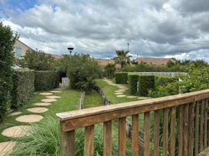 a wooden fence in a garden with grass and bushes at La maison du bonheur in Mèze