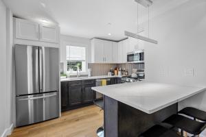a kitchen with white cabinets and a stainless steel refrigerator at Cambridge Boston 3BR2Bth Parking W&D Subway AC in Somerville