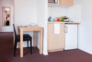 a small table with a chair next to a kitchen at Aparthotel Adagio Access Saint Louis Bâle in Saint-Louis