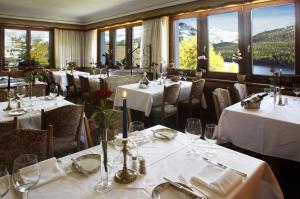 a restaurant with white tables and chairs and windows at Soldanella in St. Moritz