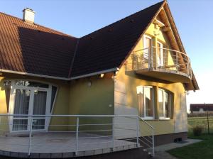 a yellow house with a balcony and a brown roof at Babati Apartmanház in Zalakaros