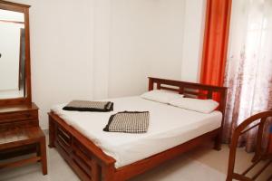 een slaapkamer met een bed met witte lakens en een spiegel bij Hidden heaven holidays and camping organisers in Haputale