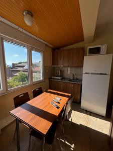 a kitchen with a wooden table and a white refrigerator at Cicek Aile Pansiyonu in Burhaniye