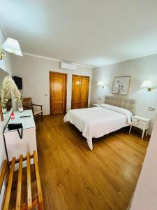 a bedroom with a large white bed and wooden floors at Hotel Salvador in Bail&eacute;n