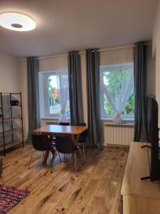a dining room with a table and two windows at Lipowy Kąt in Gołdap