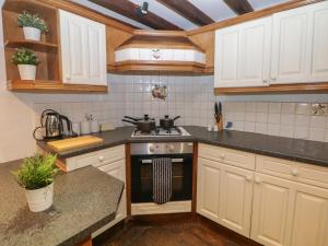 une cuisine avec des armoires blanches et un four à plaques de cuisson dans l'établissement Whim Cottage, à Hathersage