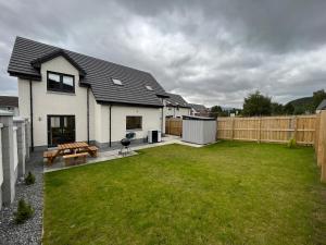 a backyard with a house and a wooden fence at The Beech House in Aviemore
