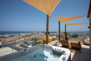 a hot tub on a balcony with a view of the ocean at Rettimo Suites, experience Luxury in the Heart of Rethymno in Rethymno Town