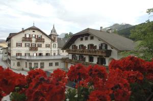 a building with red flowers in front of it at Hotel Bachmann in Villabassa