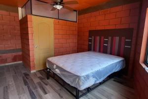Habitación pequeña con cama en una pared de ladrillo en Oasis, en Buena Vista