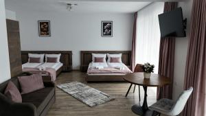 a living room with two beds and a table at Pensiunea Royal Panzió in Praid