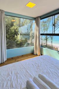 a bedroom with a large window and a large bed at Graffi Beach House in Florianópolis