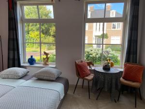 a bedroom with a bed and two chairs and a window at Room D no bathroom, geen badkamer in Aalten