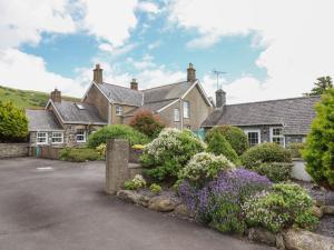 an old house with a garden in front of it at Ty Llaeth Cottage in Tywyn