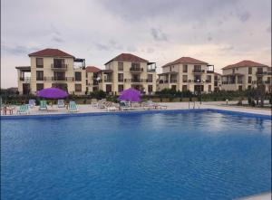 a large pool with chairs and umbrellas in front of buildings at Buzovna Delmar Luxury Residence in Mərdəkan