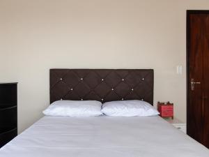 サン・フランシスコ・ド・スルにあるPiso superior:casa aconchegante à beira mar XS7441のベッド1台(白い枕2つ、茶色のヘッドボード付)