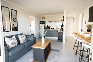 a living room with a blue couch and a kitchen at Ocean Whisper Unit 79 in Hermanus