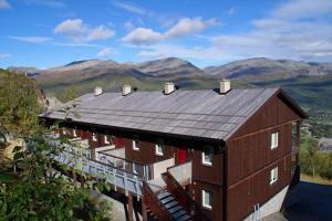a large red building with a balcony and mountains in the background at Skarsnuten Panorama 61, Hemsedal in Hemsedal +33 photos