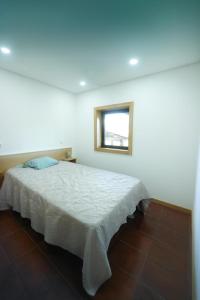a bedroom with a white bed with a window at Quintinha de Sá in Arnoso